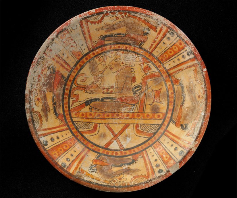 Monivärinen kolmijalkainen lautanen, jossa neljä Pawahtun-jumalaa istuvan nuoren ylimyksen ympärillä. Mayakulttuuri, Guatemala. Klassisen kauden myöhäisvaihe, 600–800 jaa. Keramiikka.