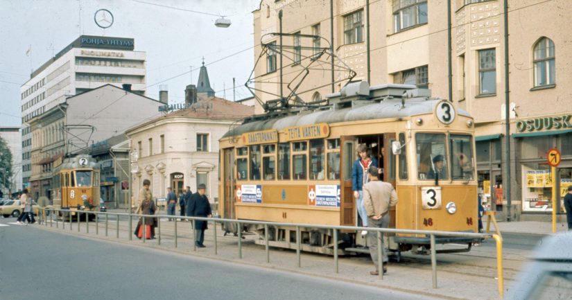 Raitiovaunu nro 3 pysäkillä ja nro 2 saapumassa Turun kauppatorin pysäkille.